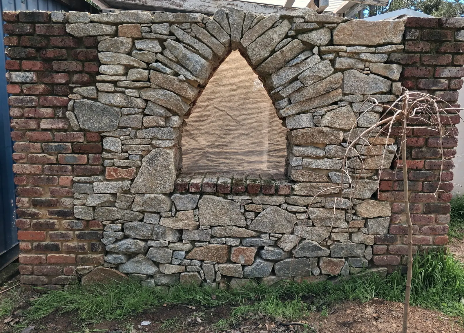 A dry stone and reclaimed brick wall with a hand-cut pointed niche